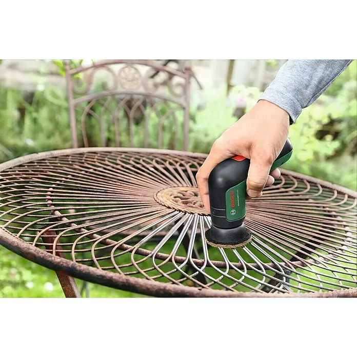 Bosch Akku-Reinigungsbürste UniversalBrush - 7 -tlg., 3,6 V, 1,5 Ah - Rost entfernen mit dem Bosch UniversalBrush Akku-Reinigungsschrubber, um eine alte Metalltischplatte in einem Garten zu restaurieren.