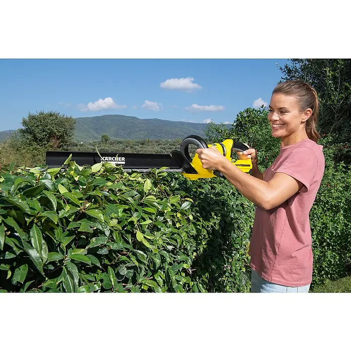 Kärcher Akku-Heckenschere HGE 18-50 Battery Set - 18 V, Li-Ionen, 1 Akku, Schnittlänge: 50 cm - Frau schneidet eine Hecke mit einer Kärcher Akku-Heckenschere, die sich durch ihr geringes Gewicht auszeichnet. Die Heckenschere sorgt für präzise Schnitte.