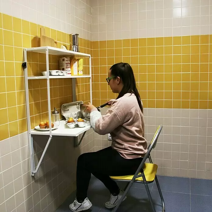 Simonrack Simonflex Estantería metálica - Al x An x Pr: 112,5 x 80 x 40 cm, Blanco - Escritorio plegable blanco de pared con estantes, utilizado por una mujer para preparar magdalenas.