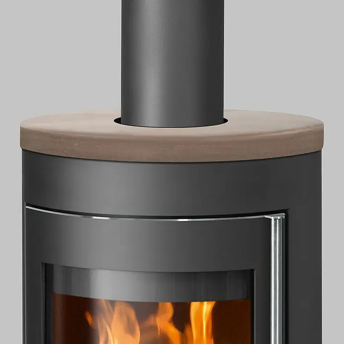 Justus Kaminofen Meva - 5,5 kW, Raumheizvermögen: 88 m³, Farbe Verkleidung: Grappa, Schwarz - Detailansicht eines modernen Kaminofens mit Steinplatte und sichtbarem Flammenspiel. Der Kaminofen präsentiert elegantes Design und Wärme.