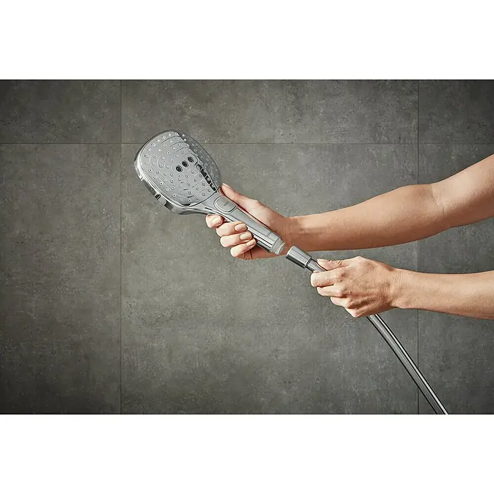 Hansgrohe Handbrause Raindance Select E 120 - Anzahl Funktionen: 3 Stk., Durchmesser: 12 cm, Chrom - Eine Handbrause mit Schlauch vor einer grauen Wand wird von zwei Händen gehalten. Das Produkt scheint neu und unbenutzt zu sein.