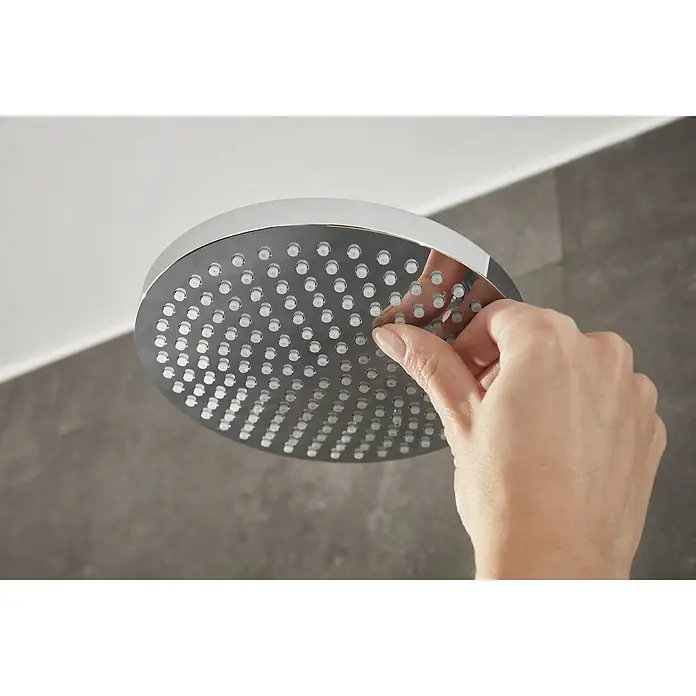 Hansgrohe Duschsystem Croma Showerpipe 160 - Mit Thermostatarmatur, Lochabstand: 93,2 cm, Anzahl Strahlarten: 4 Stk., Chrom, Höhe: 110,1 cm - Nahaufnahme eines runden, verchromten Duschkopfes, bei dem eine Hand die Düsen reinigt. Ideal für modernes Baddesign.