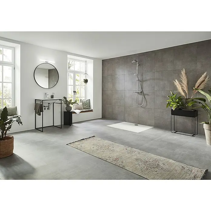 Hansgrohe Duschsystem Croma Showerpipe 160 - Mit Thermostatarmatur, Lochabstand: 93,2 cm, Anzahl Strahlarten: 4 Stk., Chrom, Höhe: 110,1 cm - Ein modernes Badezimmer mit grauen Fliesen, einer freistehenden Dusche und einem Waschtisch mit rundem Spiegel. Natürliche Elemente durch Pflanzen ergänzen den Raum.
