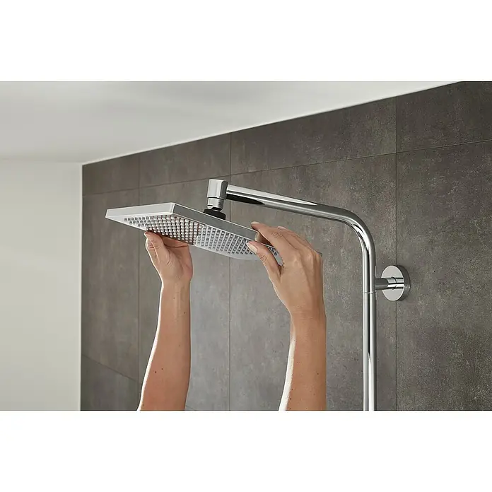 Hansgrohe Crometta Duschsystem E 240 - Mit Thermostatarmatur, Lochabstand: 103,4 cm, Anzahl Strahlarten: 2 Stk., Chrom - Nahaufnahme eines quadratischen Duschkopfs mit Händen, der eine moderne Badezimmerausstattung mit stilvollem Design hervorhebt.
