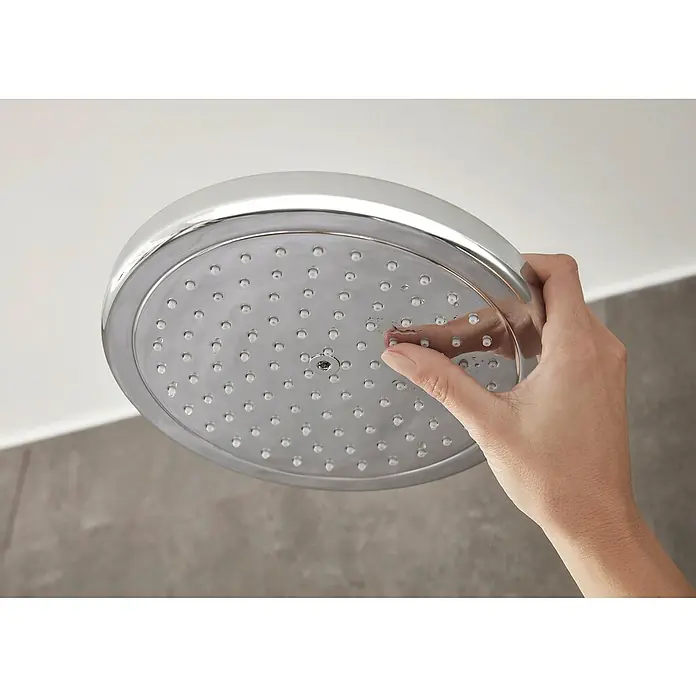 Hansgrohe Croma Duschsystem Croma Showerpipe 220 - Mit Thermostatarmatur, Lochabstand: 103,8 cm, Anzahl Strahlarten: 4 Stk., Chrom - Eine Hand berührt einen runden, silbernen Duschkopf. Der Duschkopf hat viele kleine Düsen und ein glänzendes Finish.