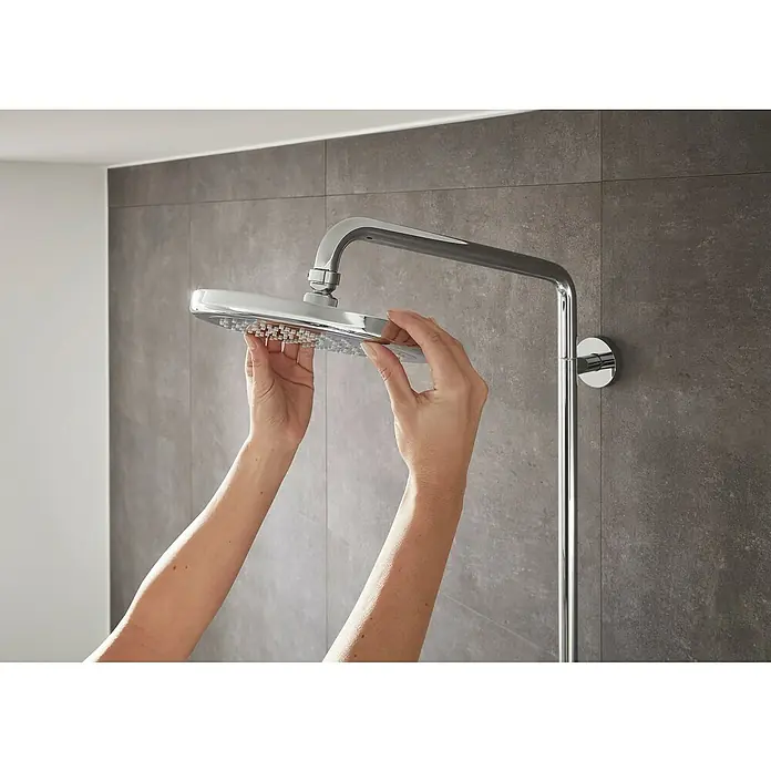 Hansgrohe Croma Duschsystem Croma Showerpipe 220 - Mit Thermostatarmatur, Lochabstand: 103,8 cm, Anzahl Strahlarten: 4 Stk., Chrom - Eine Person montiert einen glänzenden Duschkopf. Der moderne Duschkopf mit quadratischer Blende wird in einem stilvollen Badezimmer installiert.