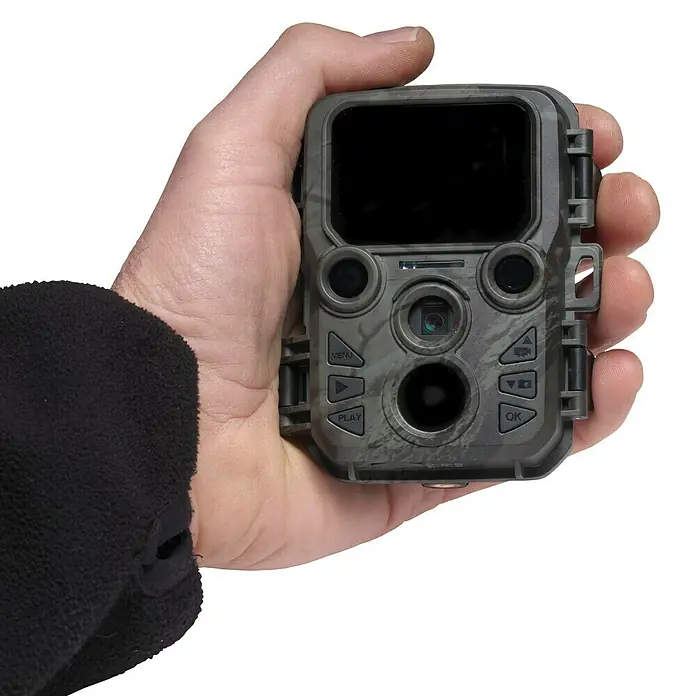 Denver Wildkamera Mini WCS-5020 - Grün-Grau - Nahaufnahme einer Wildkamera in der Hand. Die Kamera hat ein Tarnmuster und verschiedene Knöpfe und Funktionen.