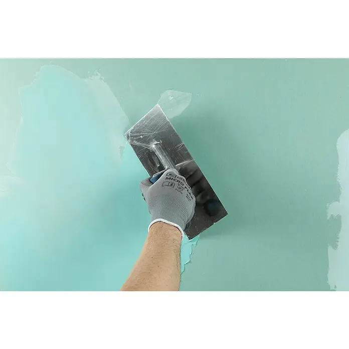 Knauf Fugenspachtel Uniflott Finish imprägniert - 6 kg - Ein Handwerker glättet mit einer Glättkelle eine mintgrüne Wand. Der Spachtel sorgt für eine ebene Fläche und ein professionelles Finish der Wand.
