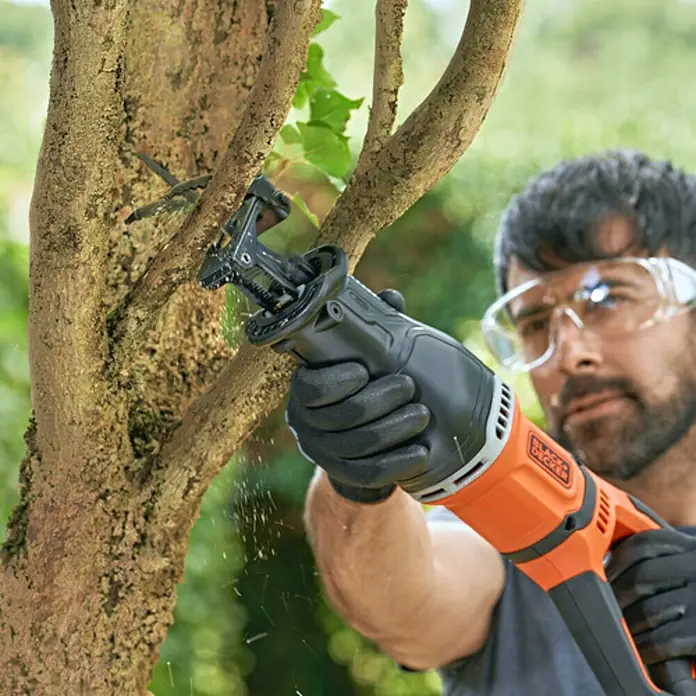 Black+Decker Sierra de sable BES301-QS - 750 W - Un hombre usa una sierra de podar BLACK+DECKER para podar un árbol, protegido con guantes y gafas.