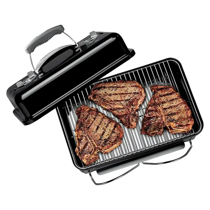 Weber Go-Anywhere Holzkohlegrill - Grillfläche (B x T): 42 x 26 cm, Schwarz - Nahaufnahme eines tragbaren Weber-Grills mit drei perfekt gegrillten Steaks, die appetitlich auf dem Rost liegen.