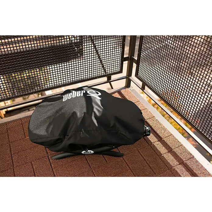 Weber Grill-Schutzhülle Standard - Passend für: Weber Q 100 Serie, Kunststoff - Abgedeckter Weber Grill auf einem Balkon mit Maschendraht-Geländer. Schutzhülle bewahrt den Grill vor Witterungseinflüssen.