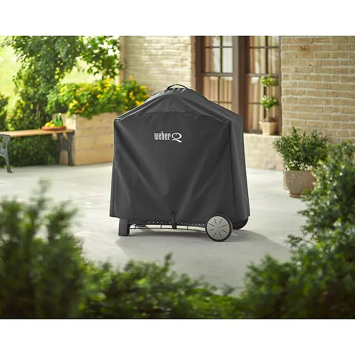 Weber Grill-Schutzhülle Premium - Passend für: Weber Q 300/3000 Serie - Abgedeckter Weber Q Grill auf einer Terrasse. Die Schutzhülle ist dunkelgrau und mit dem Weber Logo versehen. Schützt den Grill vor Wind und Wetter.