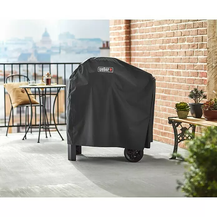 Weber Premium Grill-Schutzhülle - Passend für: Weber Pulse 1000/2000 mit Rollwagen - Schwarze Weber Grillabdeckung schützt einen Grill auf einem Balkon mit Stadtblick.