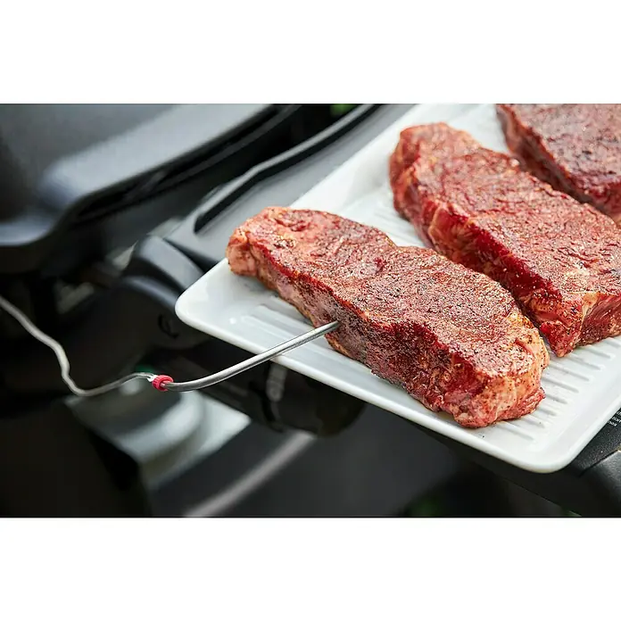 Weber Smart-Grill-Assistent - L x B x H: 9,8 x 3,4 x 7,5 cm - Nahaufnahme von drei Steaks auf einem weißen Teller mit einem Thermometer, das in eines der Steaks gesteckt wird.