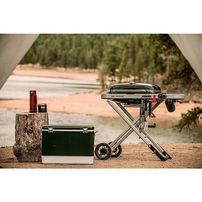 Weber Gasgrill Traveler - Grillfläche (B x T): 63 x 34 cm, 3,8 kW, Anzahl Brenner: 1, Schwarz/Silber - Camping-Szene mit Weber Traveler Grill, Kühlbox und Thermoskanne. Ideal für Outdoor-Abenteuer und Grillen in der Natur.