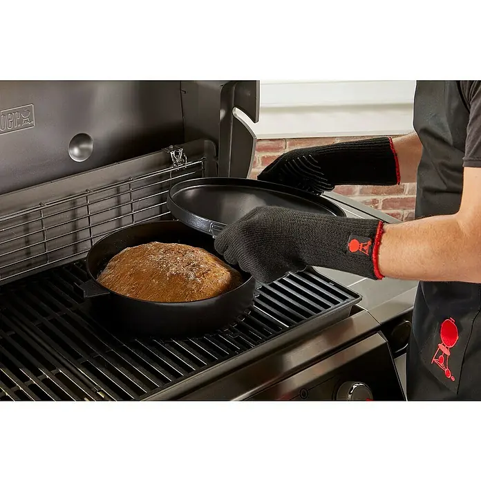 Weber Dutch Oven 2in1 - L x B x H: 33,5 x 42,37 x 12,27 cm, Gusseisen - Blick auf eine Weber Grillzubereitung mit köstlichem Brot, das in einem schwarzen Topf auf dem Grill zubereitet wird.