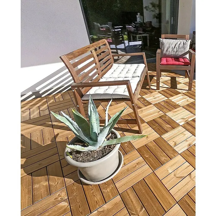 Loseta con sistema click Smartdeck - Pino, 30 x 30 x 2,5 cm, Natural, 6 ud. - Una foto de cerca de una zona exterior con un banco de madera, una silla con cojines y una planta de agave en maceta sobre una tarima de madera.