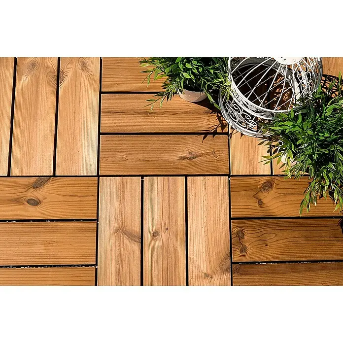 Loseta con sistema click Smartdeck - Pino, 30 x 30 x 2,5 cm, Natural, 6 ud. - Primer plano de baldosas de terraza de madera entrelazadas con plantas decorativas y una jaula decorativa.