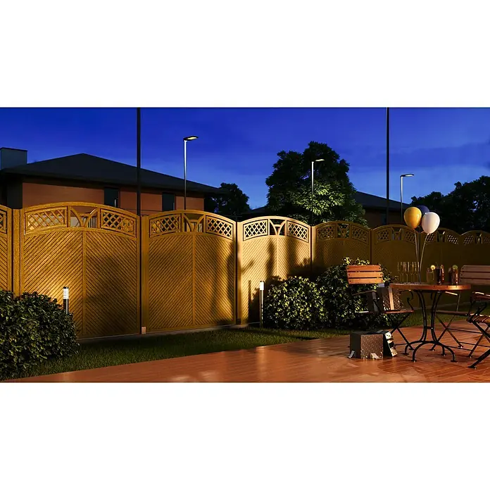 Andrewex Sichtschutzelement Toulon - 180 x 180/195 cm, Teak - Eine hölzerne Gartenzaun mit dekorativem Gitterwerk, beleuchtet durch kleine Gartenleuchten, bietet Privatsphäre und Ästhetik für den Außenbereich.