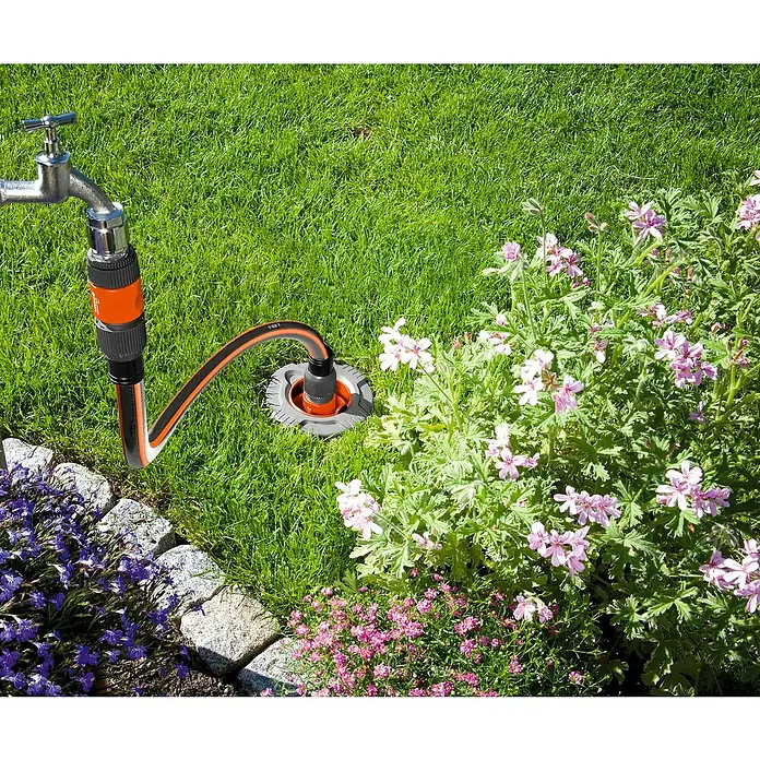 Gardena Anschlussgarnitur - Schlauchdurchmesser: 19 mm - Ein Bewässerungssystem im Garten, bestehend aus einem Wasserhahn, einem Schlauch und einer Bewässerungsstation, umgeben von Blumen und Rasen.