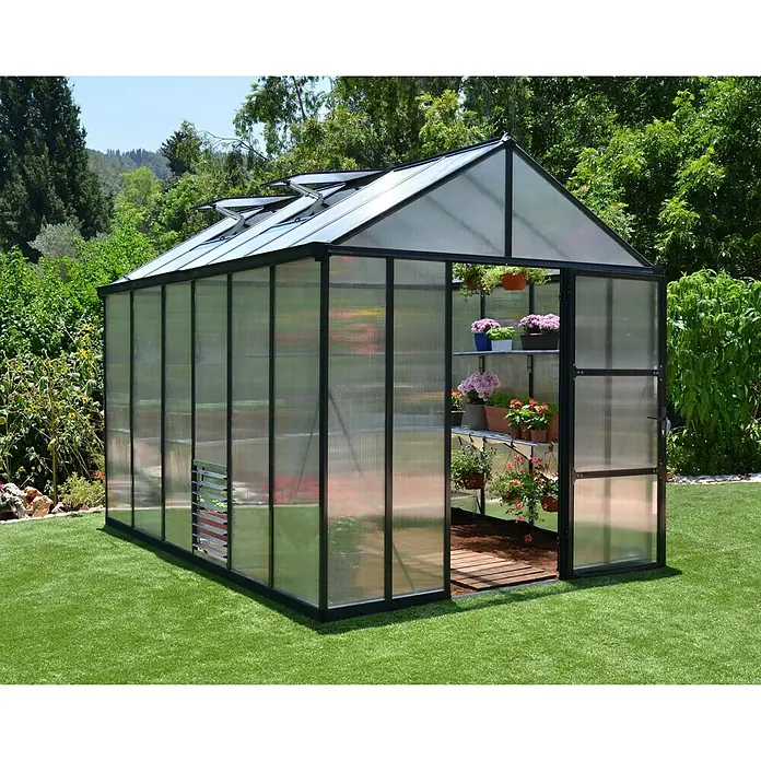 Palram – Canopia Invernadero Glory - Medidas ext. (An x Pr): 195,5 x 244,5 cm, 10 mm, Antracita - Un invernadero lleno de flores coloridas en estantes, situado en un césped verde. El invernadero tiene un marco negro robusto.