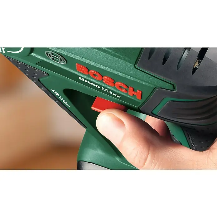 Bosch Power for All 18V Akku-Bohrhammer Uneo Maxx - 18 V, Ohne Akku, 0,6 J - Detailaufnahme eines Bosch Uneo Maxx Akku-Bohrhammers mit einem Finger auf dem roten Auslöseknopf, der das grüne Gehäuse betont.