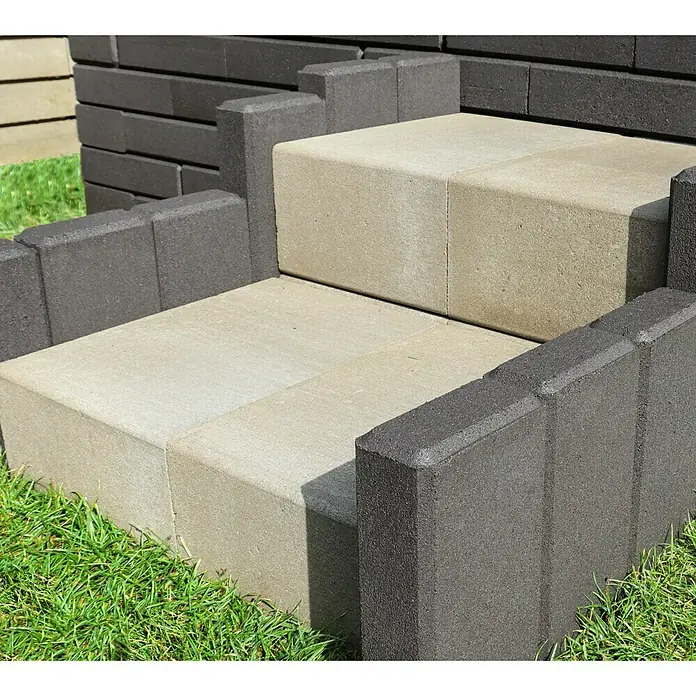 Christoph Palisade C-Line - 12,5 x 6 x 25 cm, Anthrazit, Beton - Nahaufnahme von grauen und beigen Betonpflastersteinen, die für einen Treppenabsatz verwendet werden, umgeben von grünen Grasbüscheln.