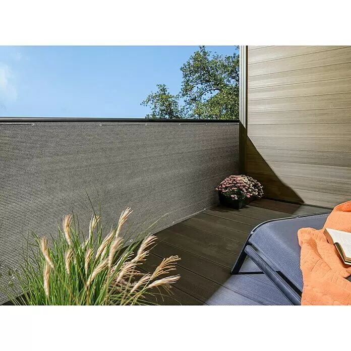 Sichtschutzmatte HDPE - 500 x 90 cm, HDPE Gewebe - Ein grauer, gewebter Balkon-Sichtschutz, an einem Balkongeländer montiert, mit Holzdeck und Liegestuhl, der Privatsphäre bietet.
