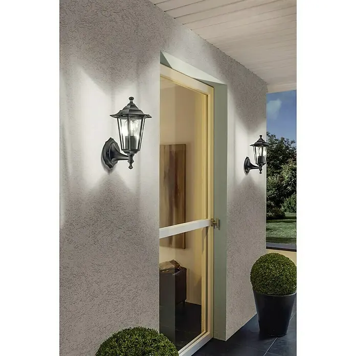 Eglo Laterna 4 Außenwandleuchte - 60 W, Schwarz, Klar, IP44, Aufwärts - Nahaufnahme von zwei eleganten schwarzen Außenwandleuchten an einer strukturierten Hauswand, die ein warmes Licht ausstrahlen.