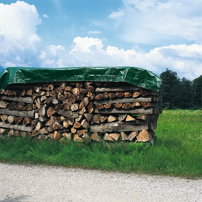 Windhager Abdeckplane Extra Heavy - 210 g/m², Kunststoff - Gestapeltes Holz unter grüner Plane. Brennholz zur Lagerung und Trocknung gestapelt und mit einer Plane vor Regen geschützt.