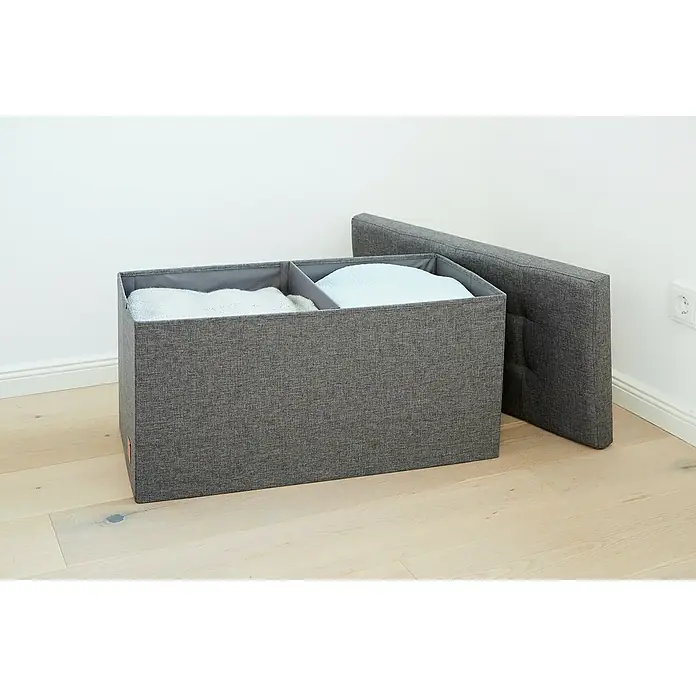 Store It Premium Sitz- & Aufbewahrungsbox Home - L x B x H: 38 x 76 x 38 cm, Grau - Graue Stoff-Aufbewahrungsbox mit zwei Fächern und einem Deckel daneben, die auf einem hellen Holzboden vor einer weißen Wand steht.
