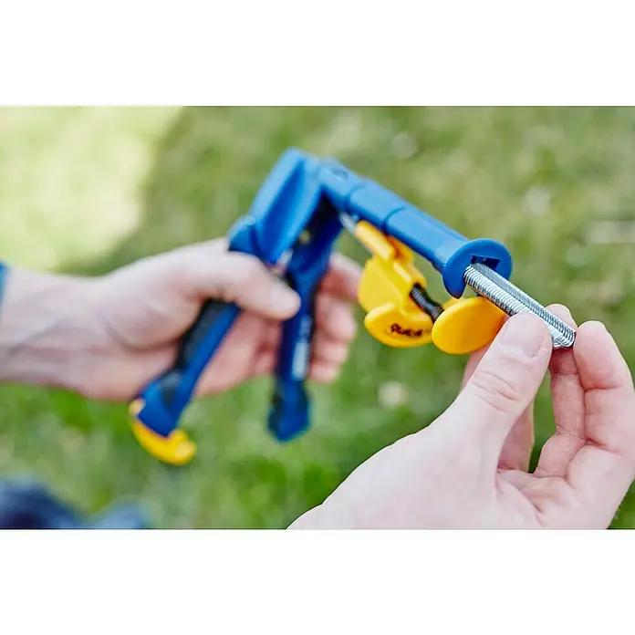 Rapid Zaunzange FP216 - Passend für: Rapid Ringklammer VR16, Ohne Ringklammern - Nahaufnahme einer Person, die ein Blindnietmuttern-Setzwerkzeug mit blauem Griff und gelben Aufsätzen bedient, um eine Schraube zu befestigen.