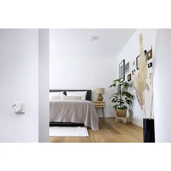 Bosch Smart Home Smart-Steckdose Kompakt - Weiß, Max. Anschlussleistung: 3.680 W - Helles Schlafzimmer mit minimalistischem Design. Ein intelligenter Rauchmelder ist an der Decke montiert, der für Sicherheit sorgt.