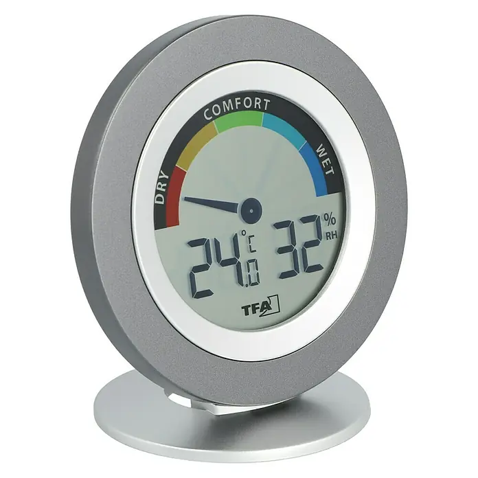 TFA Dostmann Thermo-Hygrometer Cosy - Durchmesser: 10,4 cm - Bild eines runden TFA-Hygrometers mit digitaler Anzeige für Temperatur und Luftfeuchtigkeit, das auf einer silbernen Basis steht.