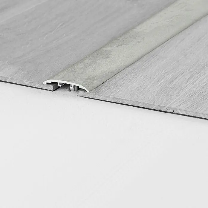 LOGOCLIC Universalprofil 3in1 Sharky Tiles - 0,9 m x 37 mm x 4,5 mm, Montageart: Schrauben - Nahaufnahme einer grauen Übergangsleiste zwischen zwei grauen Bodenbelägen, ideal für einen sauberen und professionellen Abschluss.
