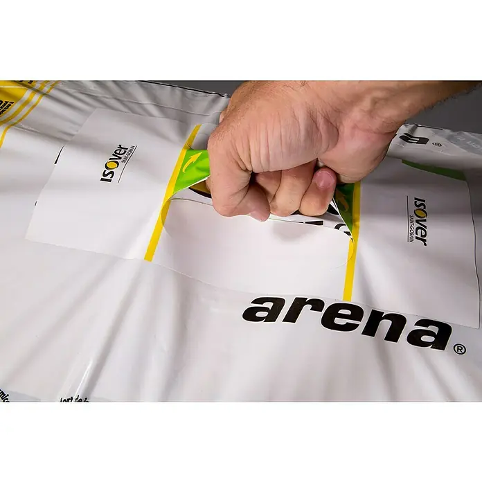 Lana mineral Arena Apta - L x An x Es: 1,35 m x 0,6 m x 4,8 cm - Primer plano del embalaje de aislamiento Isover Arena con una mano sujetando el asa, lo que facilita el transporte del producto.
