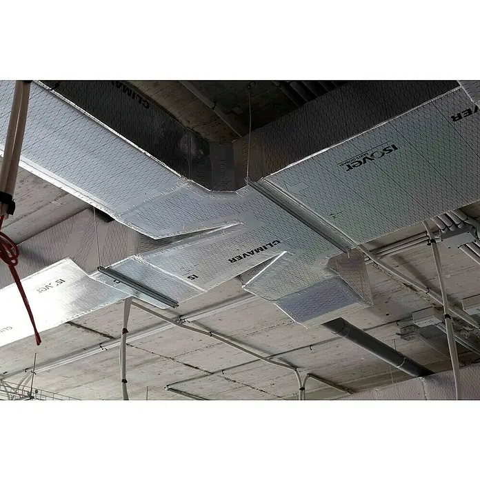 Isover Lana de vidrio Climaver Plus R - L x An x Es: 3 m x 1,19 m x 25 mm - Conductos de climatización aislados etiquetados como Isover y Climaver bajo un techo de hormigón. Tubos y conductos recorren el techo.