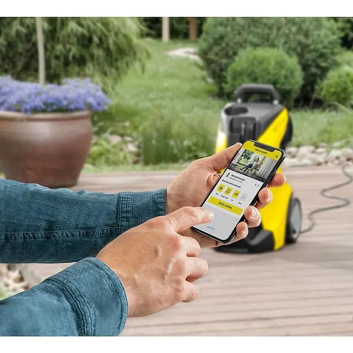 Kärcher Hidrolimpiadora de alta presión K4 Power Control - 130 bar, 1.800 W, Capacidad de bombeo: 420 l/h - Primer plano de un hombre sosteniendo un smartphone con la app Kärcher Home & Garden frente a una hidrolavadora Kärcher.