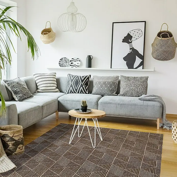Alfombra de vinilo Living Geométrica - Beige/Marrón, 290 x 200 cm - Salón con sofá gris, cojines estampados y una alfombra marrón con diseño geométrico.