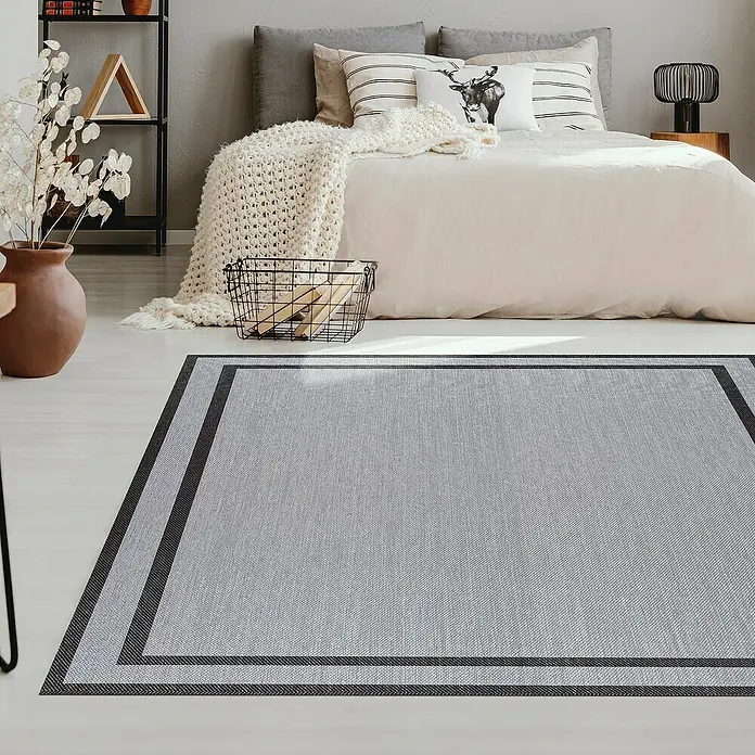 Alfombra de vinilo Marco - Plata, 230 x 160 cm - Una alfombra gris con bordes oscuros se encuentra en un dormitorio debajo de una cama, añadiendo un toque moderno a la habitación.