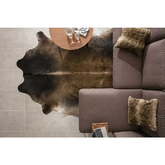 Feinsteinzeugfliese Beton - 30 x 60 cm, Grau, Matt - Ein stilvoller Raum mit einem braunen Kuhfellteppich, einem Couchtisch mit Gläsern und einer modernen Couch mit Kissen.