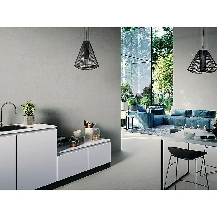 Feinsteinzeugfliese Arkety Slim - 59 x 120 cm, Grau, Matt - Ein helles, modernes Interieur mit grauen Wandfliesen, einer weißen Küchenzeile und minimalistischen Pendelleuchten. Der Boden ist passend gefliest.