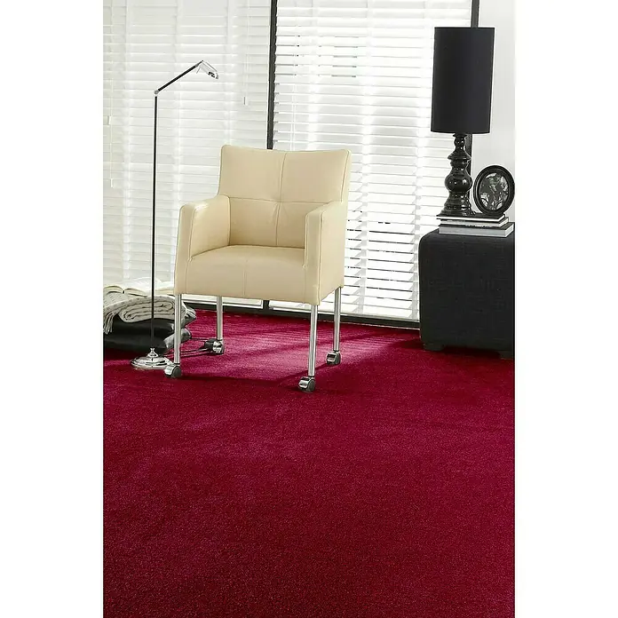 Teppichboden Meterware Linda - Breite: 400 cm, Velours, 100 % Polypropylen, Weinrot - Beiger Bürostuhl mit Chromgestell auf einem roten Teppich. Eine Lampe und ein Hocker stehen daneben.