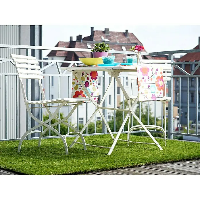 Kunstrasen Olympic - 200 x 100 cm, Grün - Ein weißer Gartentisch mit Stuhl auf einem Balkon, dekoriert mit farbenfrohen Accessoires und Kunstrasen für eine gemütliche Atmosphäre.