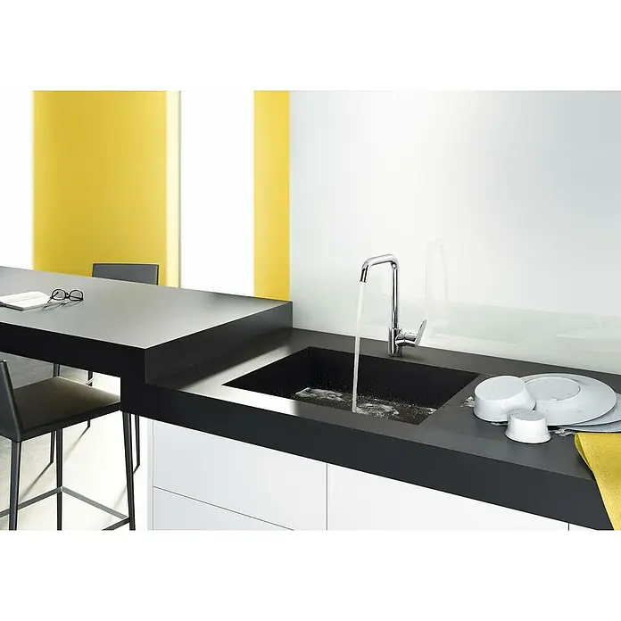Hansgrohe Spültischarmatur Focus M41 - U-Auslauf, Chrom, Glänzend - Moderne Küche mit schwarzer Spüle und chromfarbener Armatur, Wasser läuft. Geschirr und gelbes Tuch liegen daneben. Helle Einrichtung.