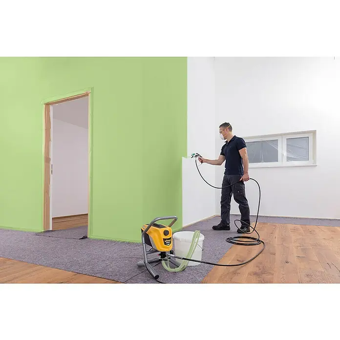 Wagner High Efficiency Airless Farbsprühsystem Control Pro 250 M - 550 W, Förderleistung: 1,25 l/min - Ein Mann sprüht mit einer Wagner Farbspritzpistole in einem Raum, wobei die Maschine gut sichtbar im Vordergrund steht.