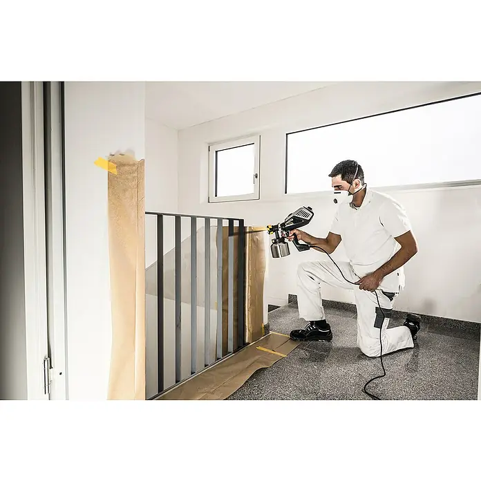 Wagner XVLP Farbsprühsystem FinishControl 3500 - 700 W - Maler mit Farbspritzgerät beim Lackieren eines Treppengeländers, geschützt mit Maske und Schutzkleidung.
