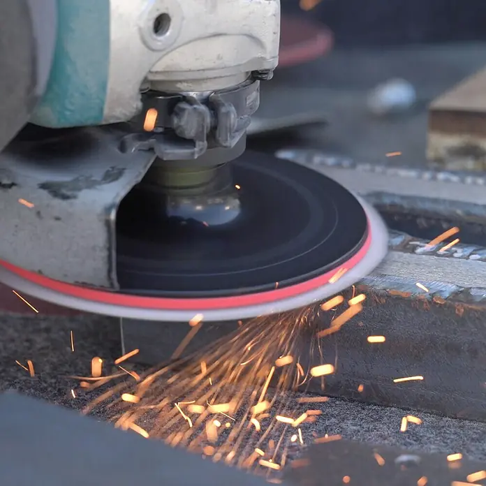 Gummischleifteller - Durchmesser: 125 mm, Durchmesser Schaft: 8 mm - Nahaufnahme eines Winkelschleifers beim Bearbeiten von Metall, wobei Funken sprühen und die rotierende Schleifscheibe im Fokus steht.