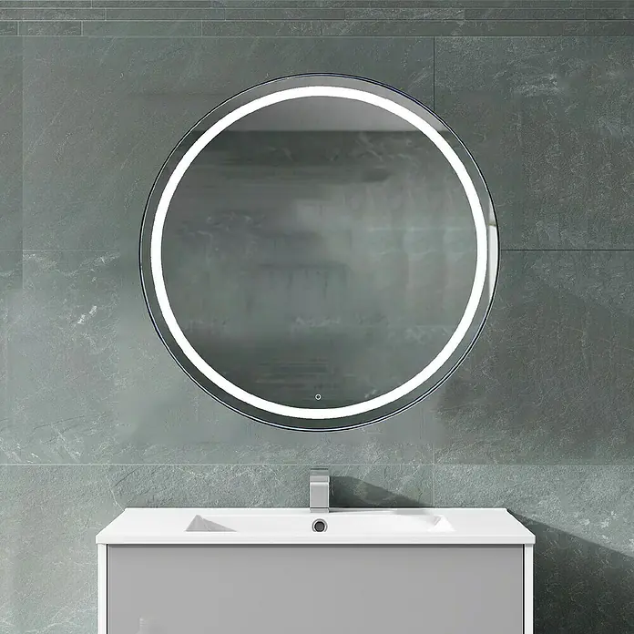 Espejo con luz Ogun - Diámetro: 60 cm, Cromo, Bombillas y tubos - Un espejo redondo iluminado con LED cuelga sobre un moderno lavabo gris con un elegante grifo, realzando el diseño del baño.