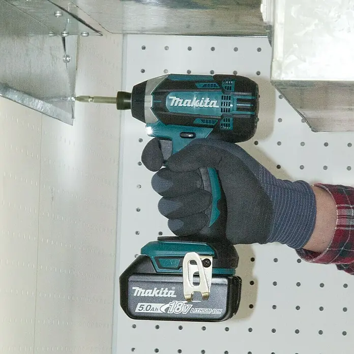 Makita Set taladro percutor de batería DTD152Z + taladro combinado DHP482Z - 18 V, 3 baterías, 3 Ah - Primer plano de un atornillador de impacto inalámbrico Makita en acción. La herramienta se está utilizando en una obra.